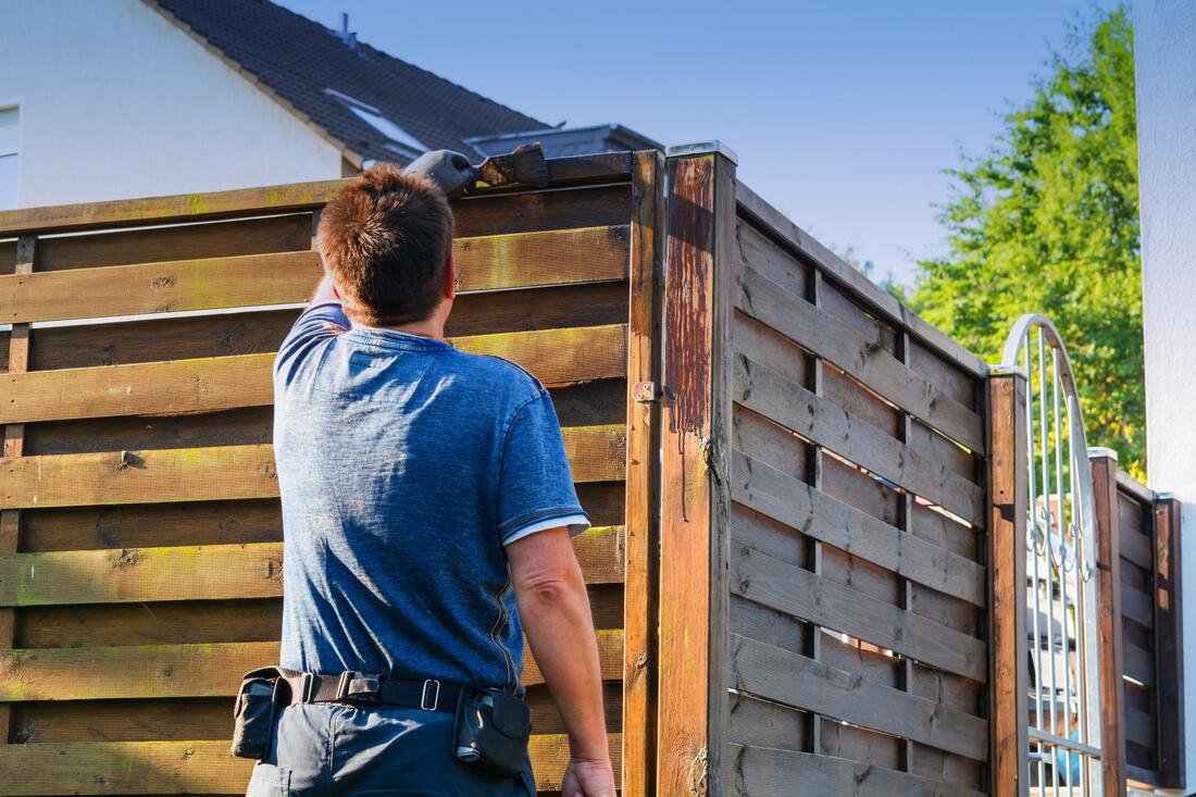 man stains the wood fence